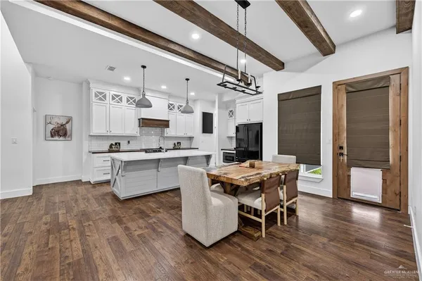 a kitchen with stainless steel appliances kitchen island granite countertop a stove top oven a sink dishwasher a dining table and chairs with wooden floor