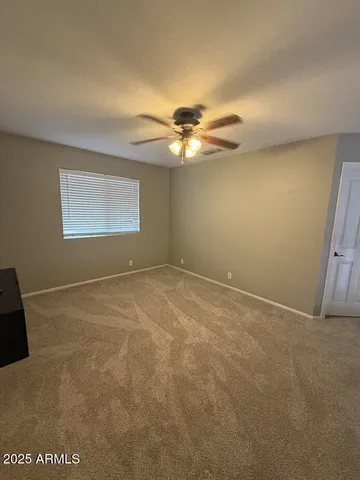 an empty room with windows and chandelier fan