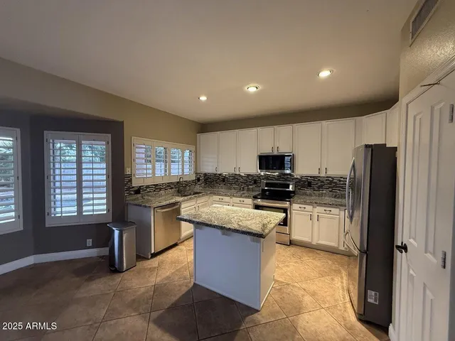 a kitchen with stainless steel appliances granite countertop a stove a sink a refrigerator and a microwave