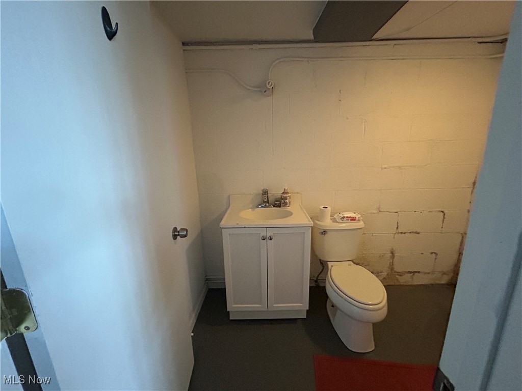 13678 Cedar Road Cleveland, OH 44118 - Photo 11 of 24 Bathroom (lower unit) in basement of lower unit featuring concrete block wall, toilet, and vanity