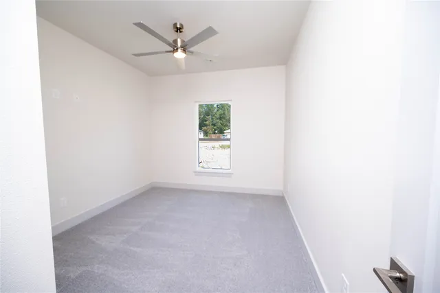 an empty room with windows and fan