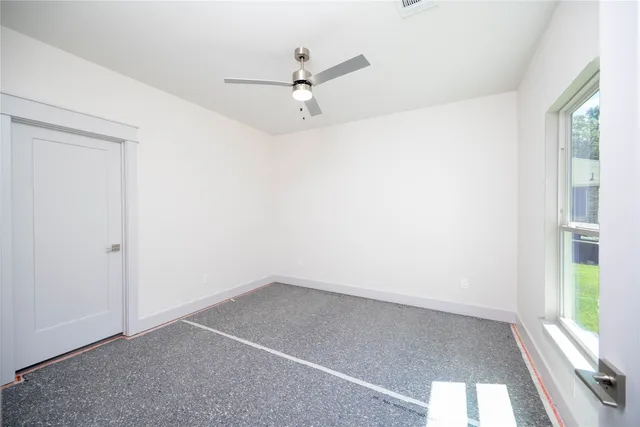 an empty room with a window and a ceiling fan
