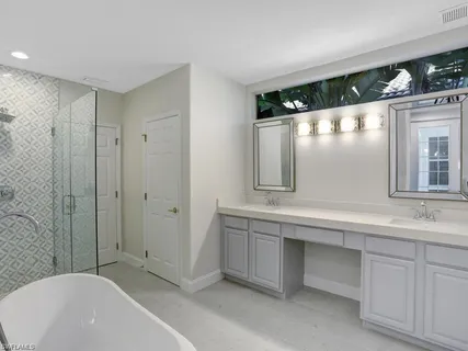 a bathroom with a double vanity sink mirror and bathtub