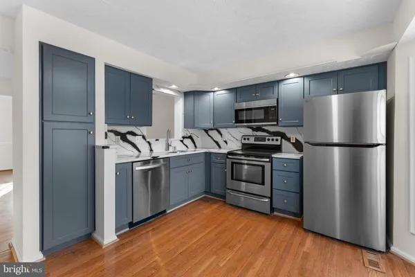 a kitchen with cabinets stainless steel appliances and wooden floor