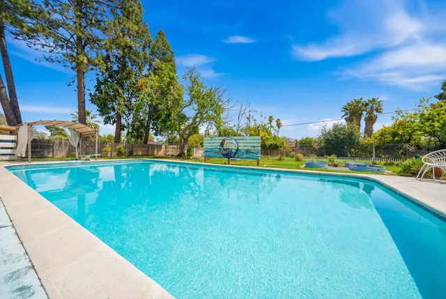 a view of swimming pool with outdoor seating and house in the background
