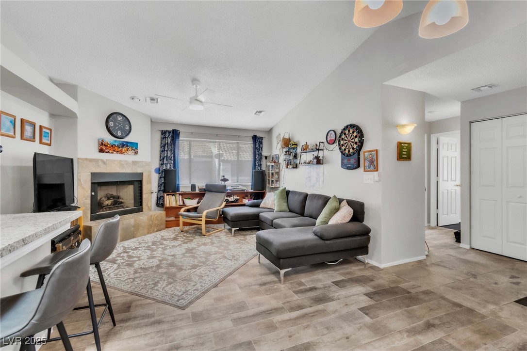 2995 East Sunset Road, Unit 235 Las Vegas, NV 89120 - Photo 10 of 24 Living area featuring a ceiling fan, a tile fireplace, wood finished floors, and vaulted ceiling
