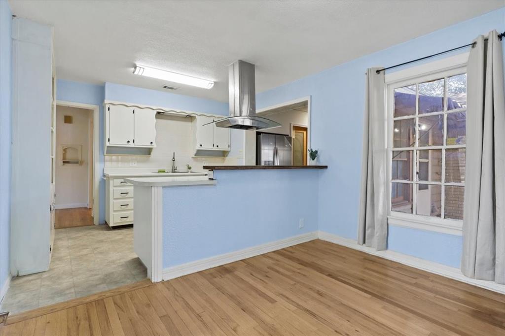 1129 North Riverside Drive Fort Worth, TX 76111 - Photo 10 of 29 a kitchen with white cabinets and wooden floor