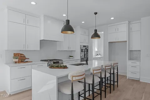 a kitchen with stainless steel appliances granite countertop a sink a stove a refrigerator and a dining table with wooden floor