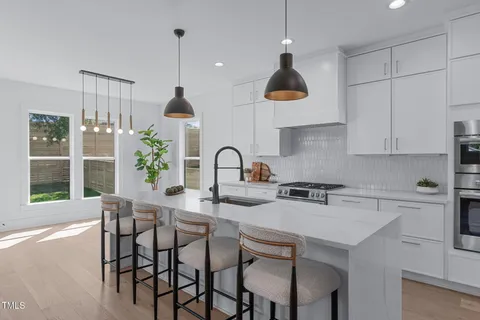 a kitchen with a sink a stove a refrigerator and white cabinets