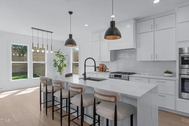 a kitchen with a sink a stove a refrigerator and white cabinets