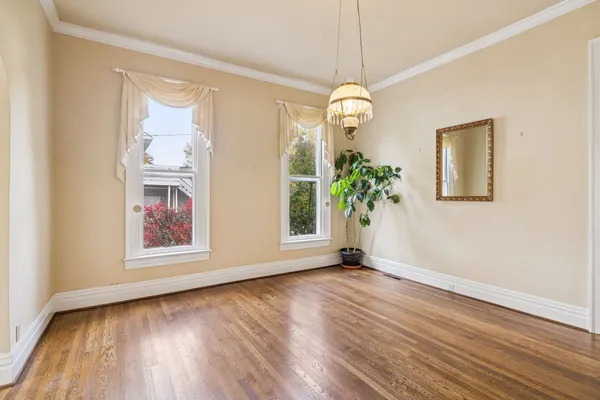a view of an empty room with wooden floor fireplace and a window