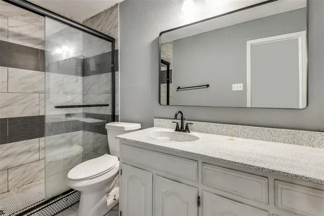 a bathroom with a granite countertop toilet sink and mirror