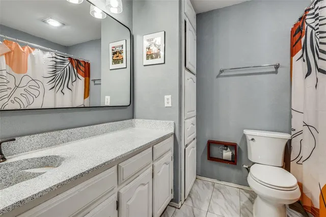 a bathroom with a granite countertop sink a toilet and a shower