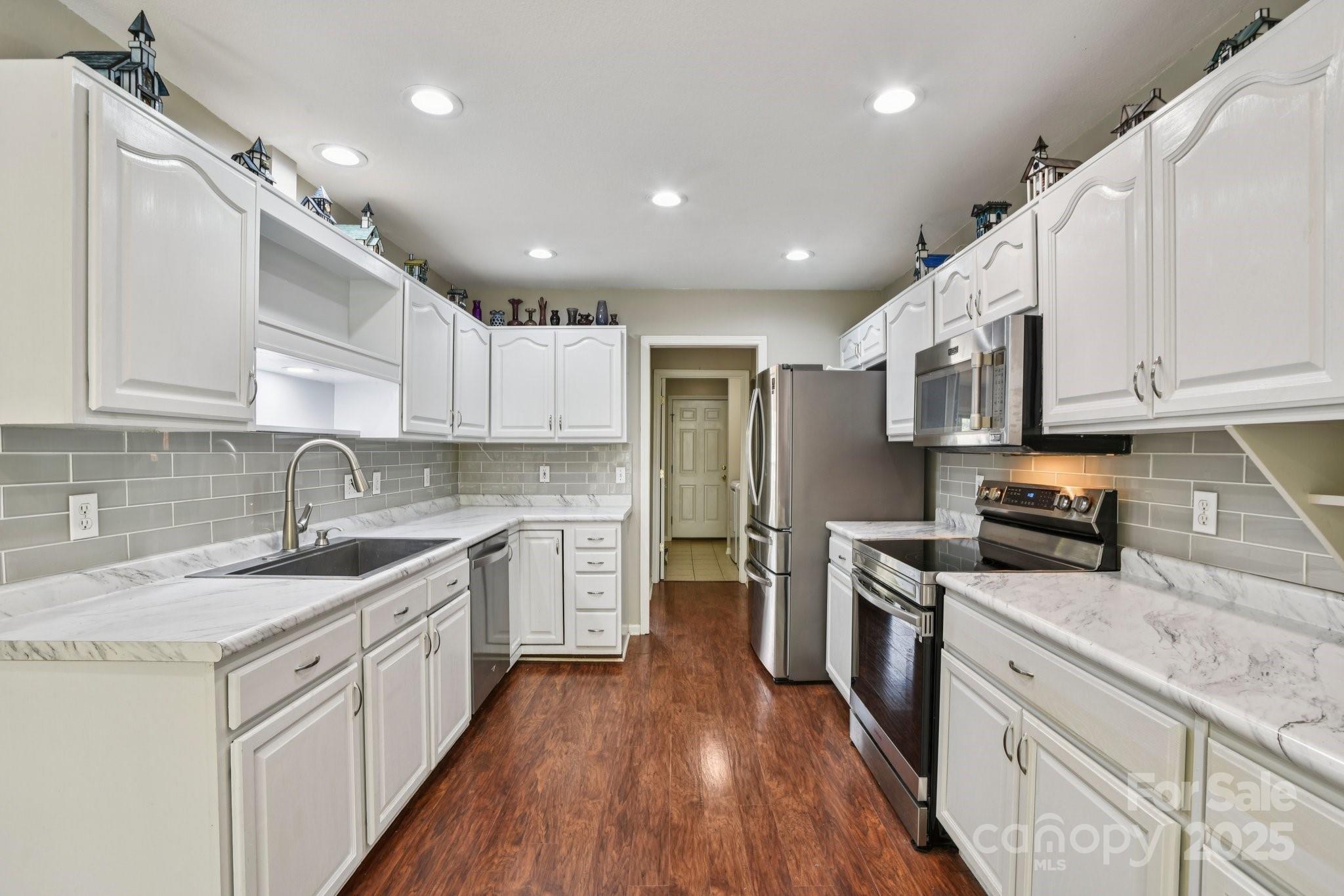 343 Stonehollow Road Fletcher, NC 28732 - Photo 6 of 36 a kitchen with stainless steel appliances granite countertop refrigerator a stove top oven a sink dishwasher and white cabinets with wooden floor