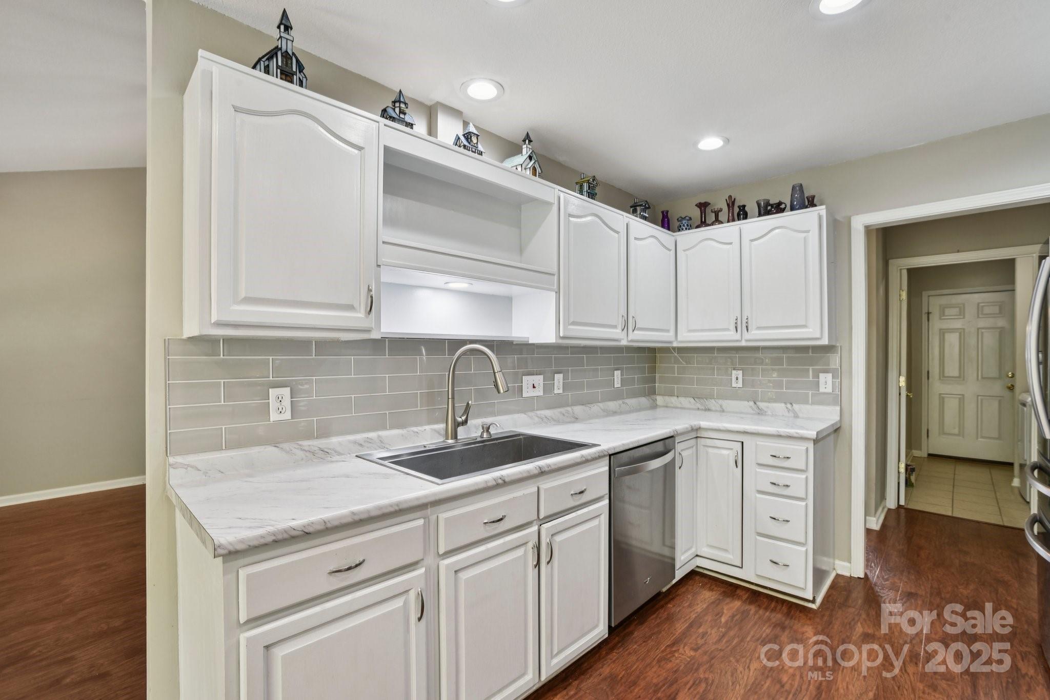343 Stonehollow Road Fletcher, NC 28732 - Photo 7 of 36 a kitchen with a sink dishwasher and white cabinets with wooden floor