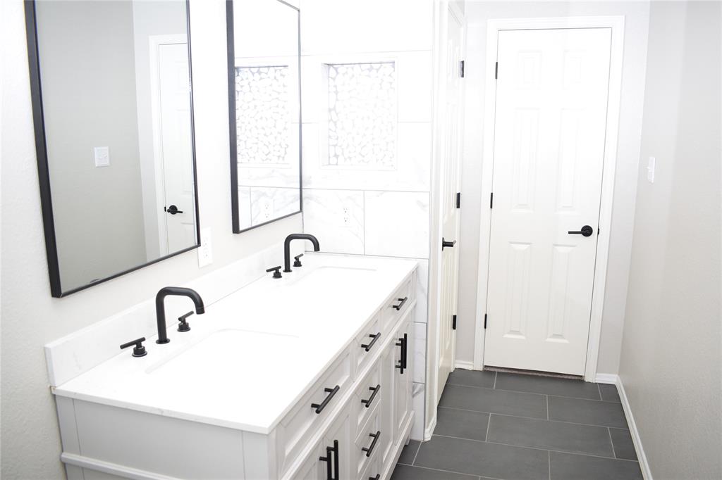 375 Housefinch Loop Leander, TX 78641 - Photo 15 of 28 Clean lines and sleek dark tile define this contemporary double vanity bathroom.