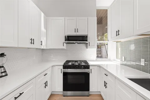 a kitchen with granite countertop white cabinets and a stove