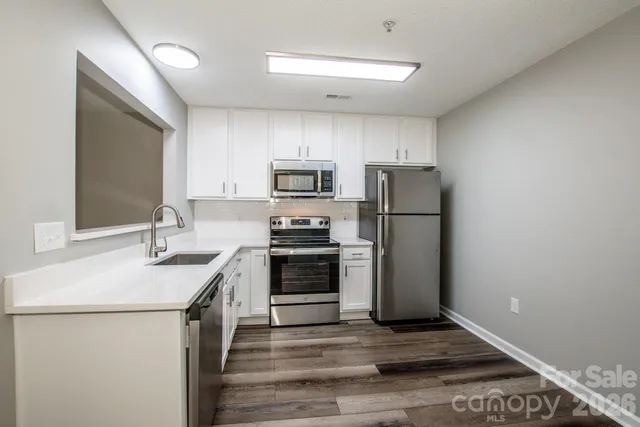 a kitchen with a sink cabinets stainless steel appliances and a counter top space