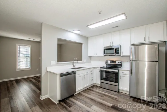 a kitchen with stainless steel appliances a stove a sink dishwasher a refrigerator and a microwave