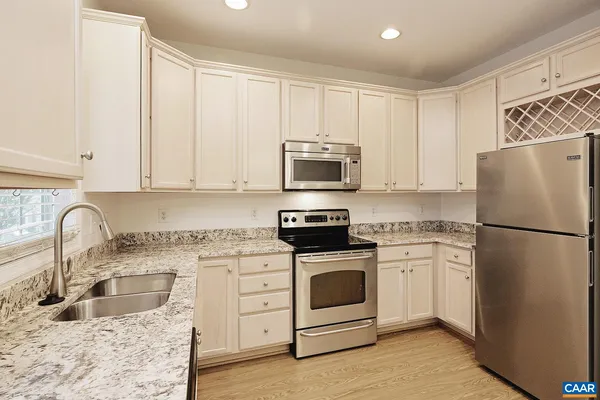 a kitchen with granite countertop a refrigerator stove and sink