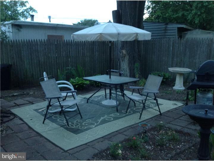 1762 Crown Point Road, Unit E9 Thorofare, NJ 08086 - Photo 5 of 23 a view of backyard with table and chairs under an umbrella with wooden fence