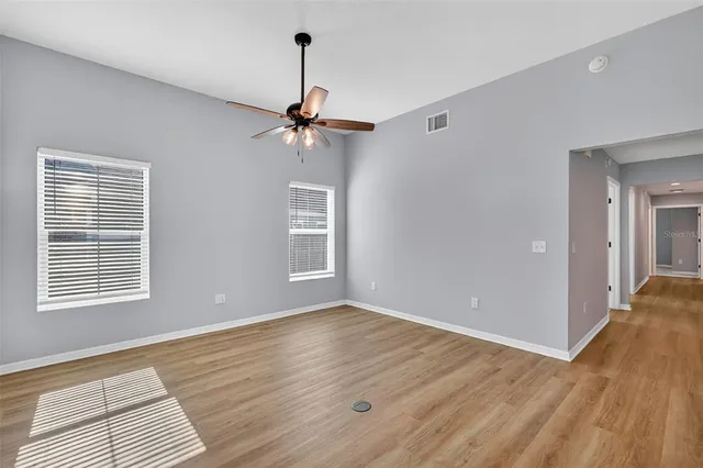 a view of an empty room with a window and wooden floor