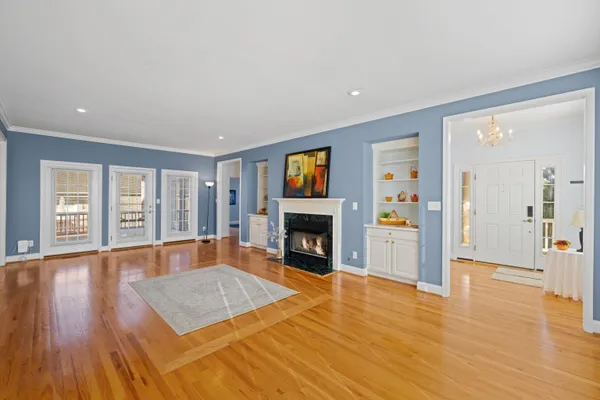 a view of an empty room with wooden floor fireplace and a window
