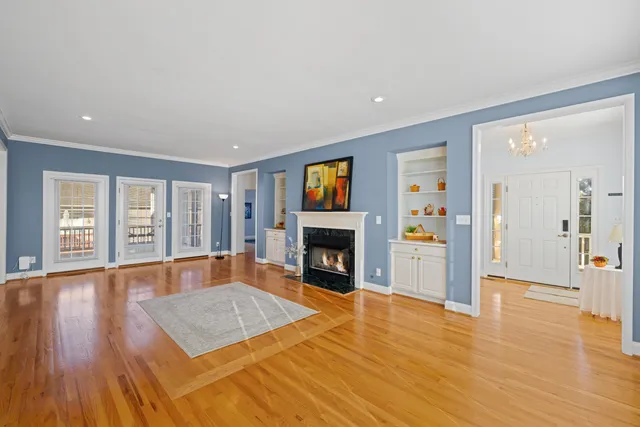 a view of an empty room with wooden floor fireplace and a window
