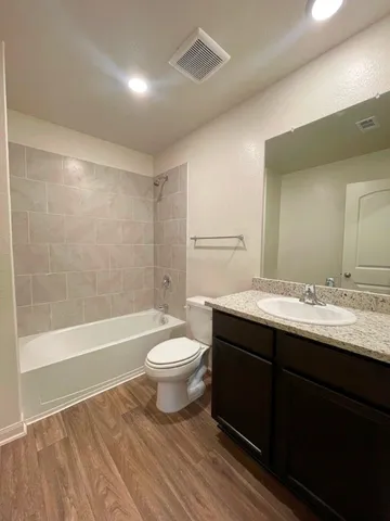 a bathroom with a bathtub shower sink vanity mirror and toilet