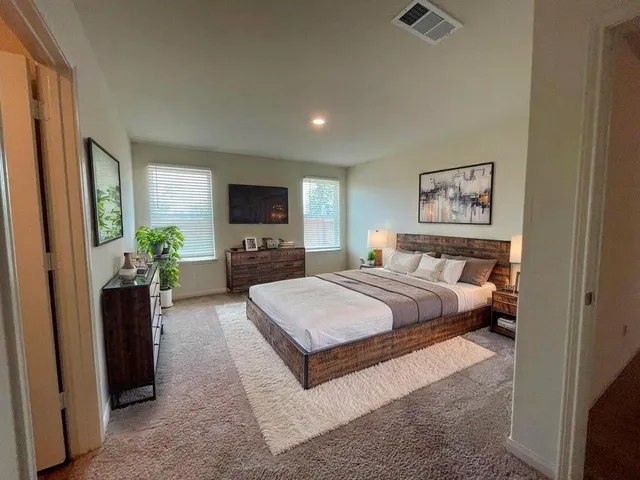 a spacious bedroom with a bed and a flat screen tv