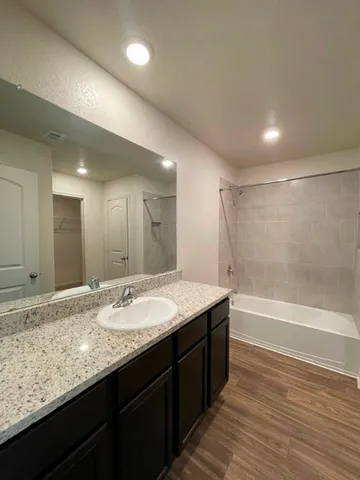 a bathroom with a granite countertop sink a large mirror and a bathtub