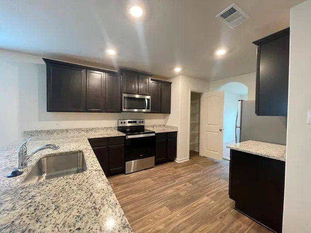 a kitchen with granite countertop a refrigerator stove top oven and sink