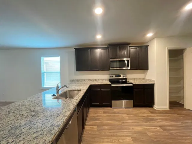 a large kitchen with granite countertop stainless steel appliances and a sink