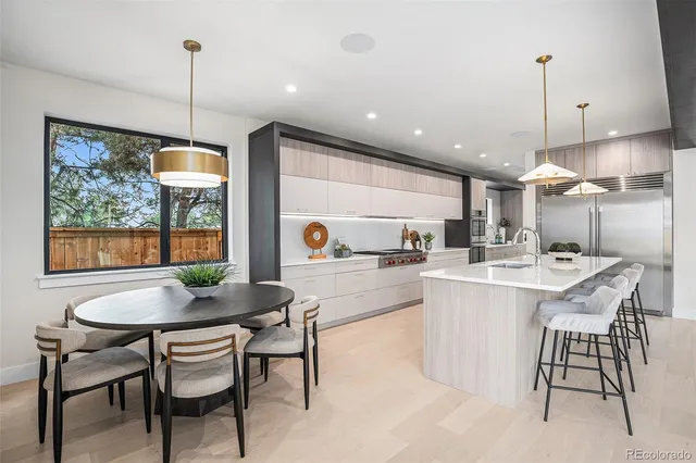 a kitchen with kitchen island a dining table chairs and white cabinets