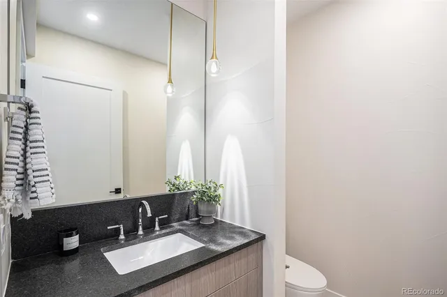a bathroom with a granite countertop sink a mirror and a toilet