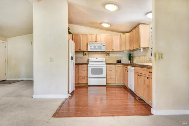 a kitchen with stainless steel appliances granite countertop a stove top oven a sink and white cabinets with wooden floor