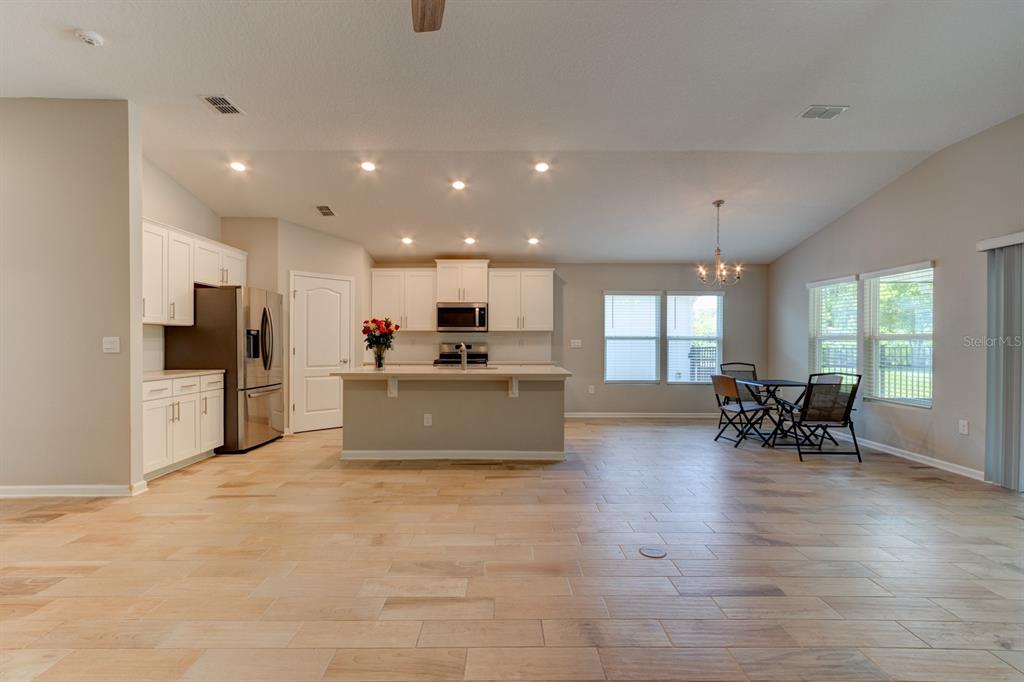 9 Ace Court Bunnell, FL 32110 - Photo 7 of 51 a large kitchen with kitchen island a island a stove a refrigerator a dining table and chairs with wooden floor