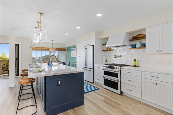 a kitchen with stainless steel appliances kitchen island granite countertop a stove a sink a refrigerator and white cabinets with wooden floor