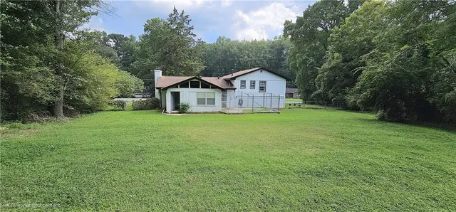 a view of a house with a big yard and large tree