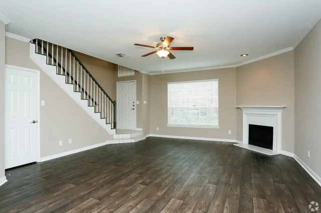a view of an empty room with wooden floor fireplace and a window