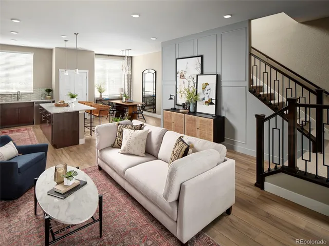 a living room with furniture kitchen view and a wooden floor