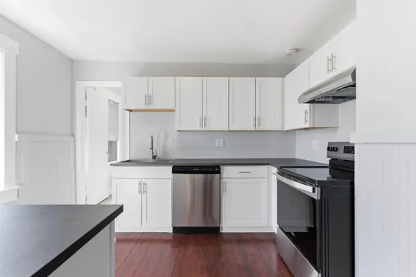 a kitchen with granite countertop a stove top oven a sink dishwasher and a refrigerator with wooden floor
