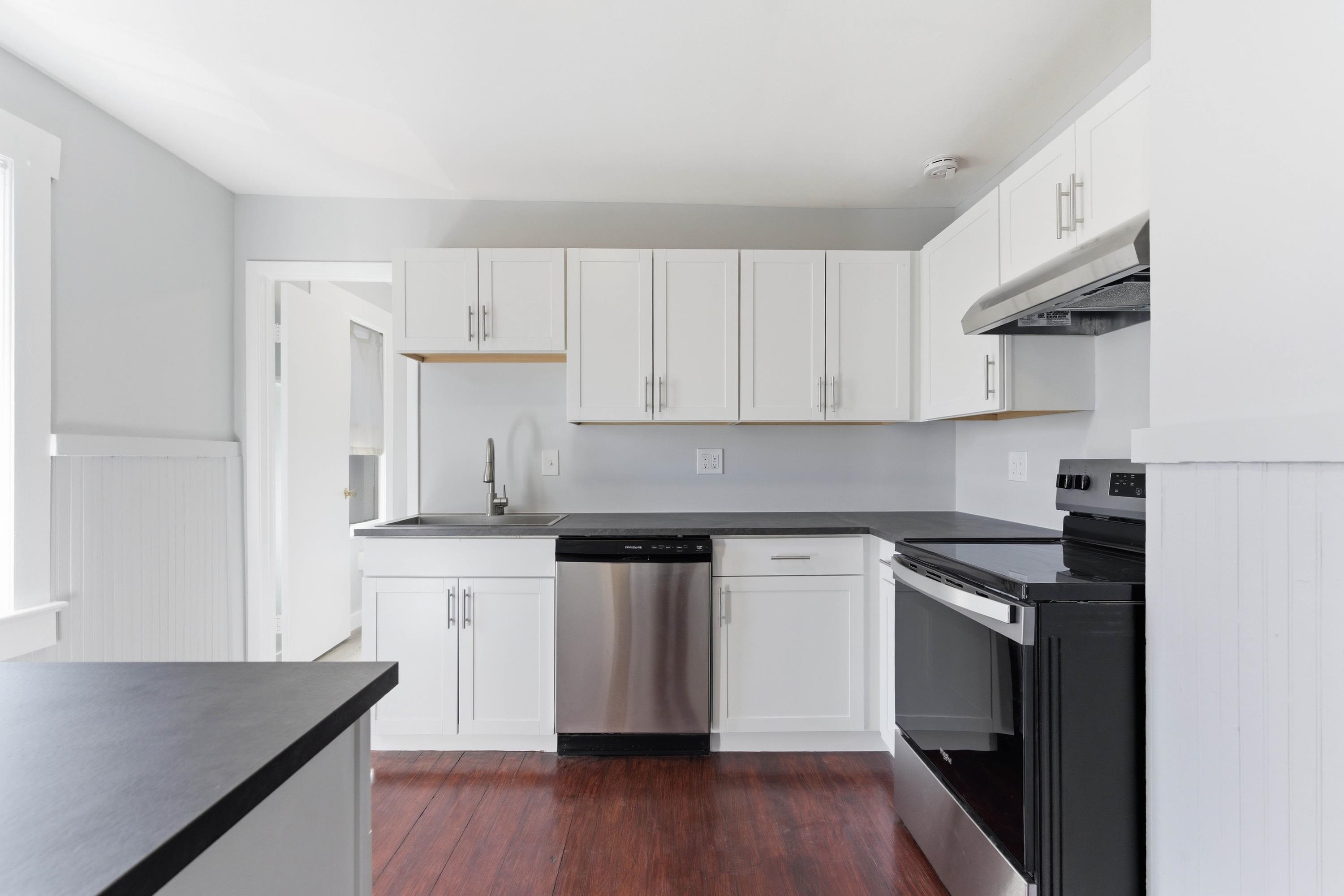 50 Saragossa Street, Unit D St. Augustine, FL 32084 - Photo 4 of 9 a kitchen with granite countertop a stove top oven a sink dishwasher and a refrigerator with wooden floor