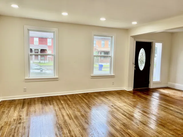 a view of an empty room with wooden floor and a window