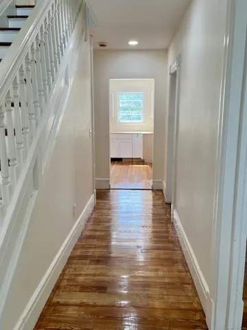 a view of a hallway with wooden floor and staircase