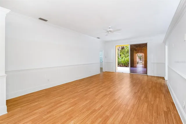 a view of empty room with wooden floor and fan