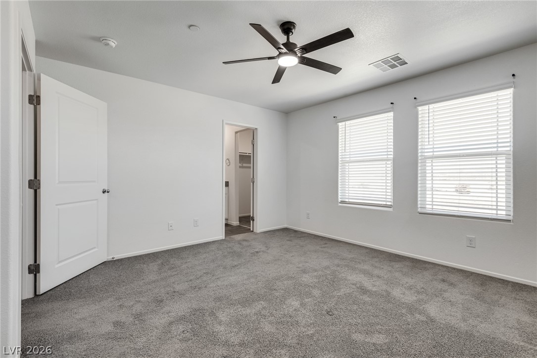 1114 Scarlet Sparrow Street Henderson, NV 89011 - Photo 16 of 25 A well-lit bedroom with fresh carpet and a modern ceiling fan, offering a serene retreat.