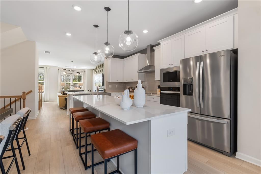 204 Daybreak Lane Newnan, GA 30265 - Photo 15 of 48 a kitchen with stainless steel appliances a refrigerator a sink dishwasher a dining table and chairs with wooden floor