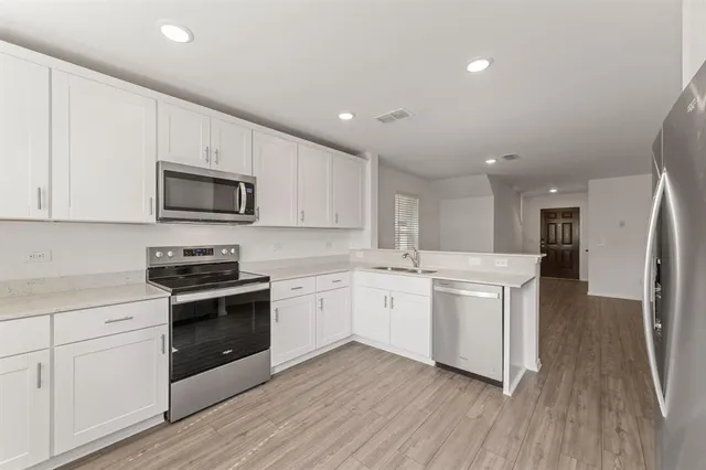 a kitchen with white cabinets stainless steel appliances and wooden floor