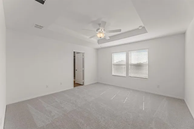 an empty room with chandelier fan and windows